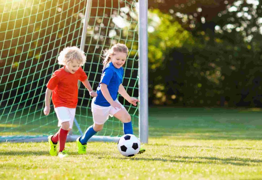 Kids play football. Child at soccer field.